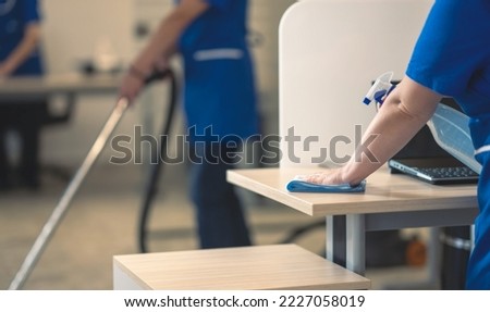 Cleaning an office table.Other cleaners clean in the background Foto d'archivio © 