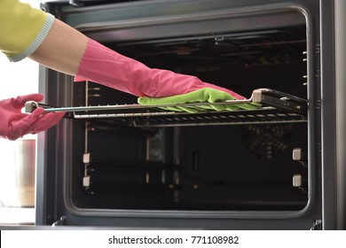 Cleaning The Oven. Woman's Hand In Household Cleaning Gloves Cleans Oven Inside. Clean Oven In Kitchen.