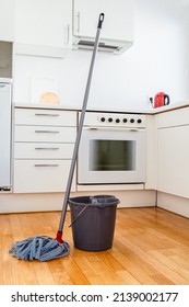 Cleaning parquet floor with rope mop. Microfiber mop with wringer and bucket of water for cleaning floor on background of kitchen