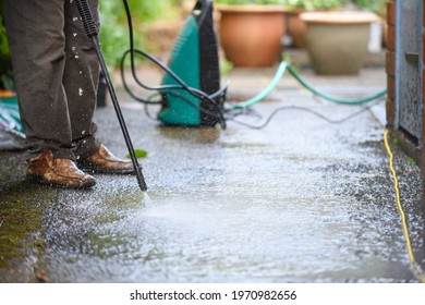 Cleaning patio paving with a high pressure washer the man is using the water to clean the garden path