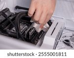 cleaning PC components with microfiber cloth, hand wiping RAM slots, inside computer case, hardware maintenance, dust removal, PC care, cleaning process, workstation