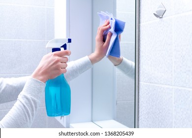 Cleaning and polish mirror with rag and spray in bathroom at home. Housekeeping and cleaning service. Clean house, cleanliness