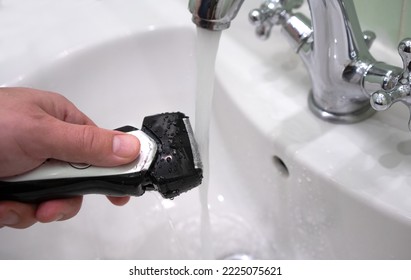 Cleaning the razor from small hairs under a stream of water in the faucet. Cleaning the electric shaver.