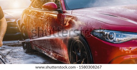 Cleaning red Car Using High Pressure Water in a Car Wash