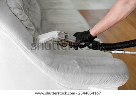 Cleaning and restoring a light-colored couch using an upholstery cleaning machine in a cozy living room
