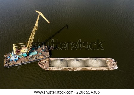 Cleaning the river bottom with a crane and a barge top view.
