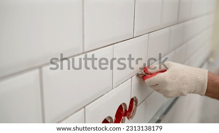 Cleaning seams after gluing ceramic tiles. Cleaning the seams of ceramic tiles. Seams between tiles in the kitchen. A man uses a knife to remove dirt. Replace old grout between tiles.