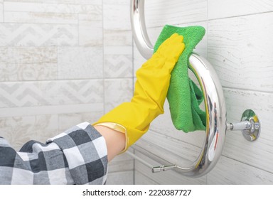 cleaning service. bathroom cleaning and disinfection. hand in yellow rubber glove wipes chrome heated towel rail in bathroom