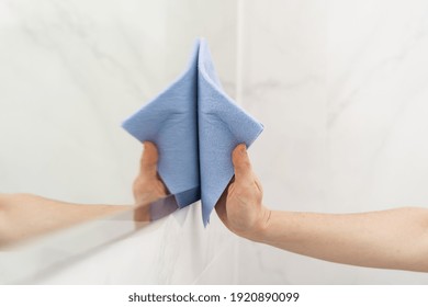 Cleaning service concept. Cropped view of woman wiping mirror with rag, standing in bathroom. Housewife make daily routine work at home - Powered by Shutterstock