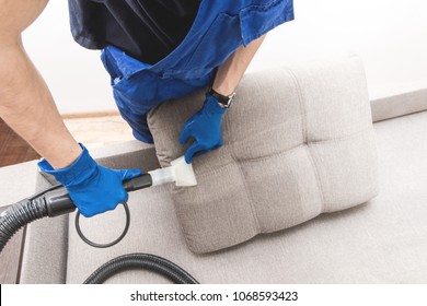 Cleaning Service. Man Janitor In Gloves And Uniform Vacuum Clean Sofa With Professional Equipment