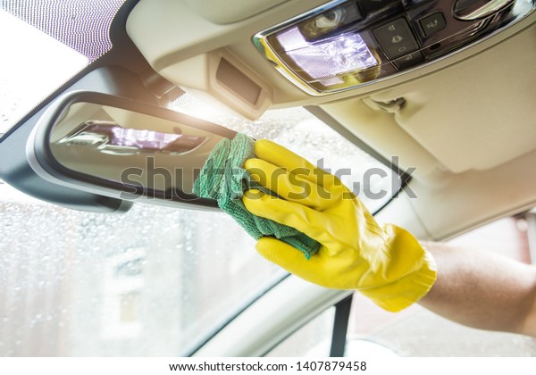Cleaning service. Man in uniform and yellow\
gloves washes a car interior in a car\
wash