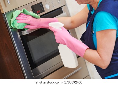 Cleaning service. Woman cleaning built-in kitchen appliances.