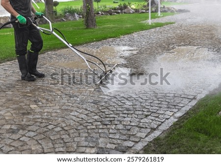Cleaning service worker using a surface cleaner attachment on a pressure washer, cleaning a cobblestone driveway