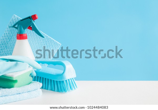 Cleaning set for different surfaces in kitchen,\
bathroom and other rooms. Empty place for text or logo on blue\
background. Cleaning service concept. Early spring regular clean\
up. Front view.