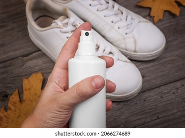 Cleaning Shoes. Close Up Of Water Repellent Shoe Spray. Rain Protection. Boots With Autumn Leaves On Wood Background. Protecting White Sneakers