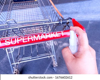 Cleaning shopping cart holder with alcohol spray. Corona Virus or bacteria infected protection from touch public object. Customer self-protection in public place concept. - Powered by Shutterstock