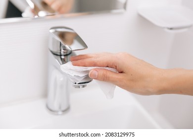 Cleaning the sink faucet with a microfiber cloth. Cleaning the bathroom. Sanitize surfaces prevention in hospital and public spaces against corona virus. Woman hand using wet wipe.