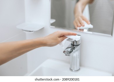 Cleaning the sink faucet with a microfiber cloth. Sanitize surfaces prevention in hospital and public spaces against corona virus. Woman hand using wet wipe. Cleaning the bathroom.