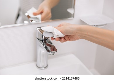 Cleaning The Sink Faucet With A Microfiber Cloth. Sanitize Surfaces Prevention In Hospital And Public Spaces Against Corona Virus. Woman Hand Using Wet Wipe. Cleaning The Bathroom.