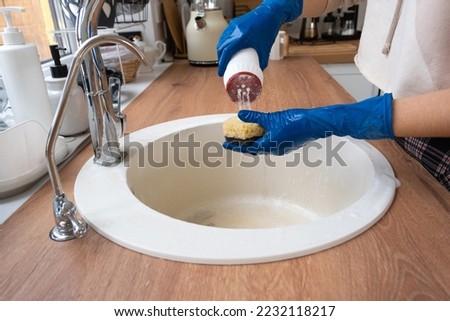 Cleaning sink in kitchen, Hand in gloves and sponge, detergent, dry powder. cozy interior of the home, restoring order, cleanliness, disinfection
