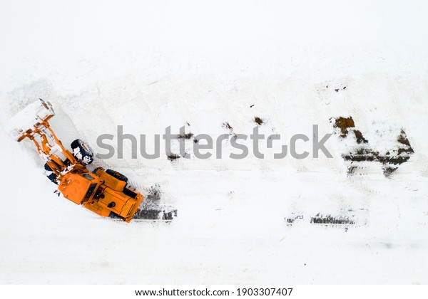 cleaning snow from the streets\
after a heavy snowfall. Tractor cleans the snow-view from the\
top.
