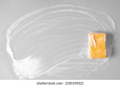 Cleaning sponge and soapy foam on gray background. Sponge, soap,  Bubbles, Cleaning service. Flat lay, top view, copy space.
