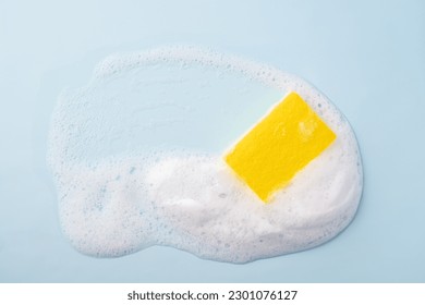 Cleaning sponge and a soapy foam on a blue background. Cleaning concept, cleaning service. Banner. Flat lay, top view