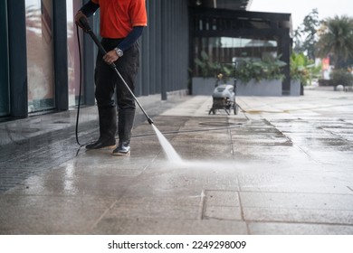 cleaning staff hoses a portable car for washing the concrete floor with high-pressure water jets. - Shutterstock ID 2249298009