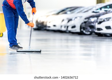 The Cleaning Staff Is Cleaning On The Work Area That Is The Epoxy Floor. In A Car Repair Shop Or Service Center The Background Is A New Car Park Waiting To Be Sold. ,Car Industry On The Epoxy Floor