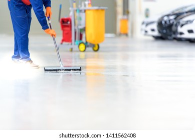 The Cleaning Staff Is Cleaning On The Work Area That Is The Epoxy Floor. In A Car Repair Shop Or Service Center The Background Is A New Car Park Waiting To Be Sold. ,Car Industry On The Epoxy Floor