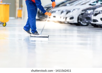 The Cleaning Staff Is Cleaning On The Work Area That Is The Epoxy Floor. In A Car Repair Shop Or Service Center The Background Is A New Car Park Waiting To Be Sold. ,Car Industry On The Epoxy Floor