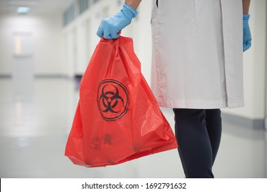 The cleaning staff is taking out the infected waste bags marked with the biohazard sign  to get rid of properly.