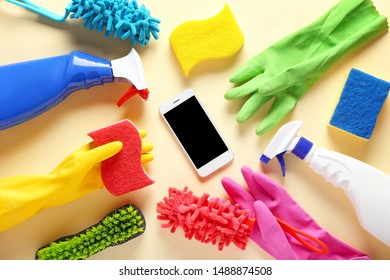 Cleaning supplies and mobile phone on color background - Powered by Shutterstock