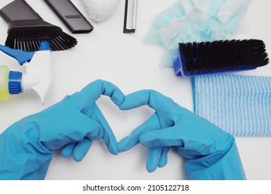 Cleaning supplies organized in a circle with hands in blue rubber gloves forming a heart