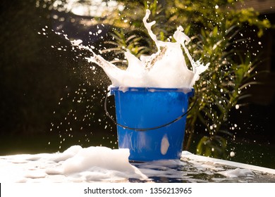 Cleaning Supply Bucket Full Of Soap Splashing Around With Green Nature Background