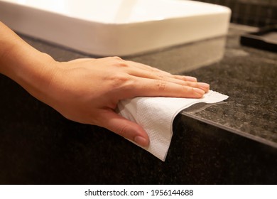 Cleaning Surface. Closeup Of Hand Using Paper Wipe Cleaning Black Marble Restroom Counter Surface. Concept Of Disinfection Surface To Prevent Coronavirus, Dust And Germs. Selective Focus