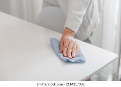 Cleaning the table with a blue microfiber cloth. Sanitize surfaces prevention in hospital and public spaces against coronavirus. Woman hand using wet wipe at home. Cleaning the room. - Shutterstock ID 2114217332