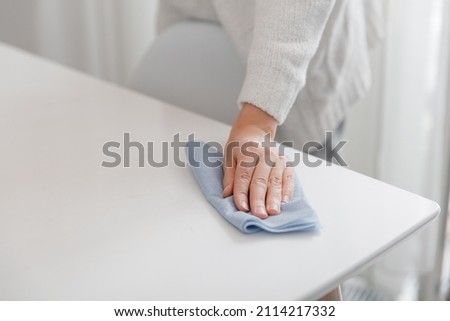 Cleaning the table with a blue microfiber cloth. Sanitize surfaces prevention in hospital and public spaces against coronavirus. Woman hand using wet wipe at home. Cleaning the room.