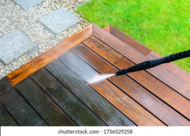 cleaning terrace with a power washer - high water pressure cleaner on wooden terrace surface