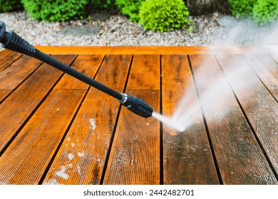 cleaning terrace with a power washer - high water pressure cleaner on wooden terrace surface - shallow depth of field