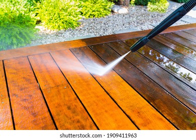 cleaning the terrace with a pressure washer - high-pressure cleaner on the wooden surface of the terrace - very shallow depth of field - sharpness on the terrace board under a stream of water