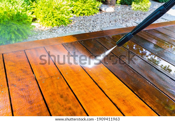 cleaning the terrace with a pressure washer -\
high-pressure cleaner on the wooden surface of the terrace - very\
shallow depth of field - sharpness on the terrace board under a\
stream of water