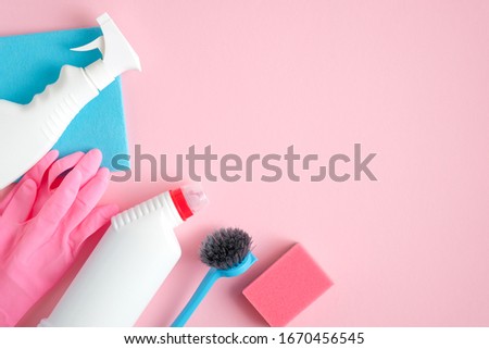 Cleaning tools on pink background with copy space. House cleaning service and housekeeping concept. Flat lay, top view.