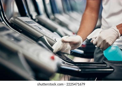 Cleaning, treadmill and sanitizing equipment in gym for bacteria, germs or protection from covid. Disinfection, sanitizer and closeup of cleaner wiping running machine for fitness in sports center. - Powered by Shutterstock