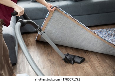  Cleaning with a vacuum cleaner under carpet in the living room. Appliances for cleaning the house. black vacuum cleaner. - Shutterstock ID 1785071792