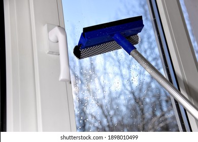 Cleaning of vinyl plastic window on blue sky background. Squeegee tool.