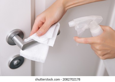 Cleaning white door handles with an antiseptic wet wipe and sanitizer spray. Disinfection in hospital and public spaces against corona virus. Woman hand using towel for cleaning home room door link. - Shutterstock ID 2082702178