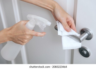 Cleaning white door handles with an antiseptic wet wipe and sanitizer spray. Disinfection in hospital and public spaces against corona virus. Woman hand using towel for cleaning home room door link. - Shutterstock ID 2083223464