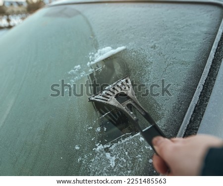 Cleaning the windshield from ice with a plastic ice scraper.