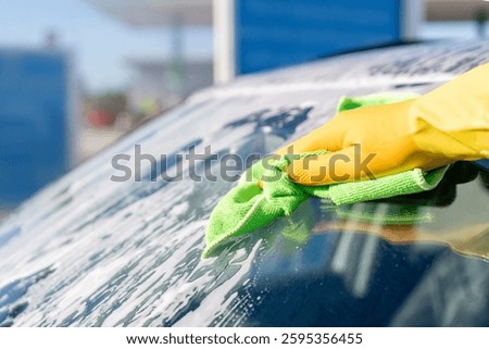 Cleaning windshield at service station using microfiber cloth on bright sunny day